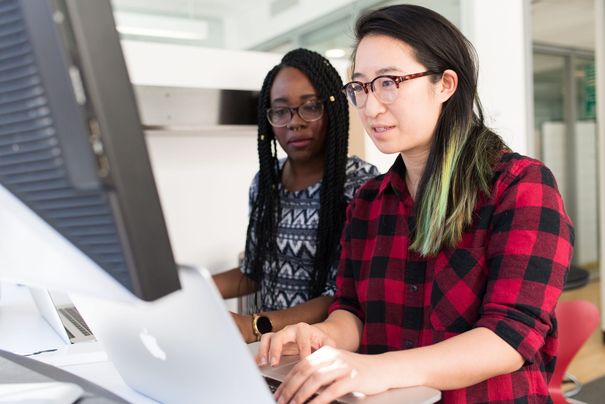 two women typing at computer